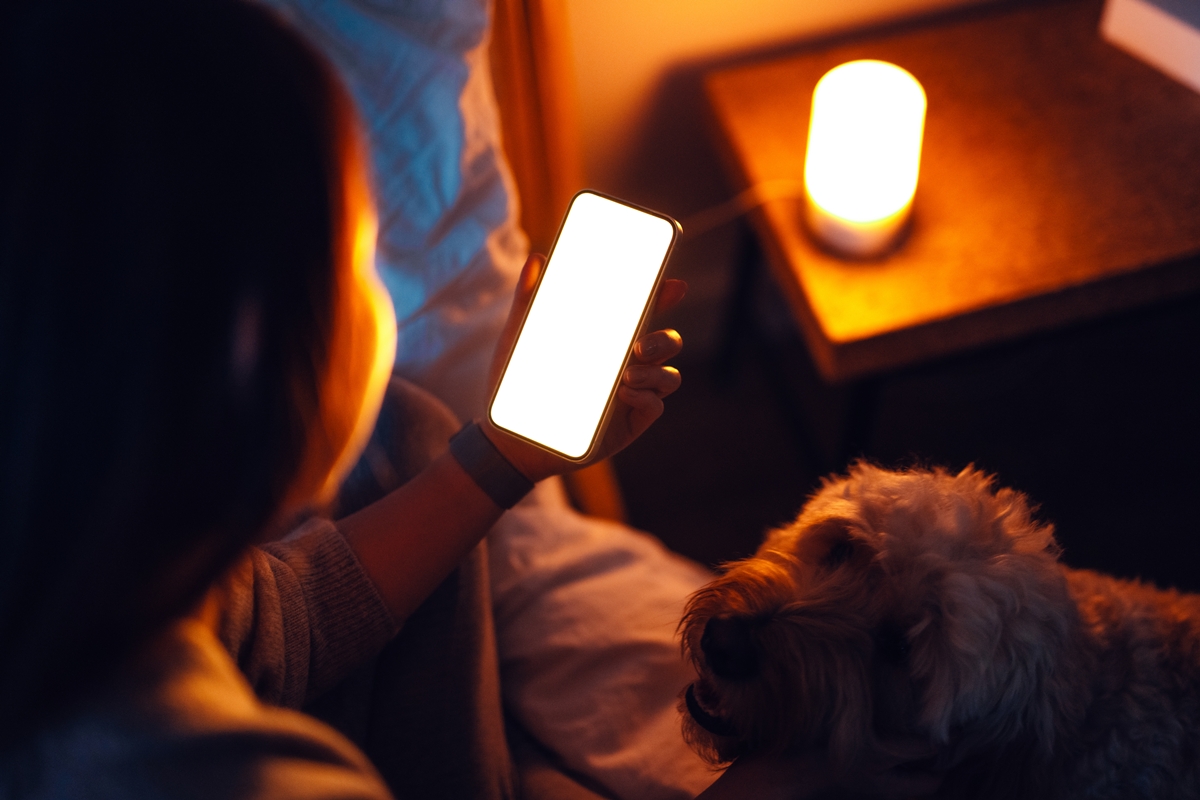 1 de 1 mulher mexendo no celular ao lado de cachorro - Foto: Oscar Wong/Getty Images