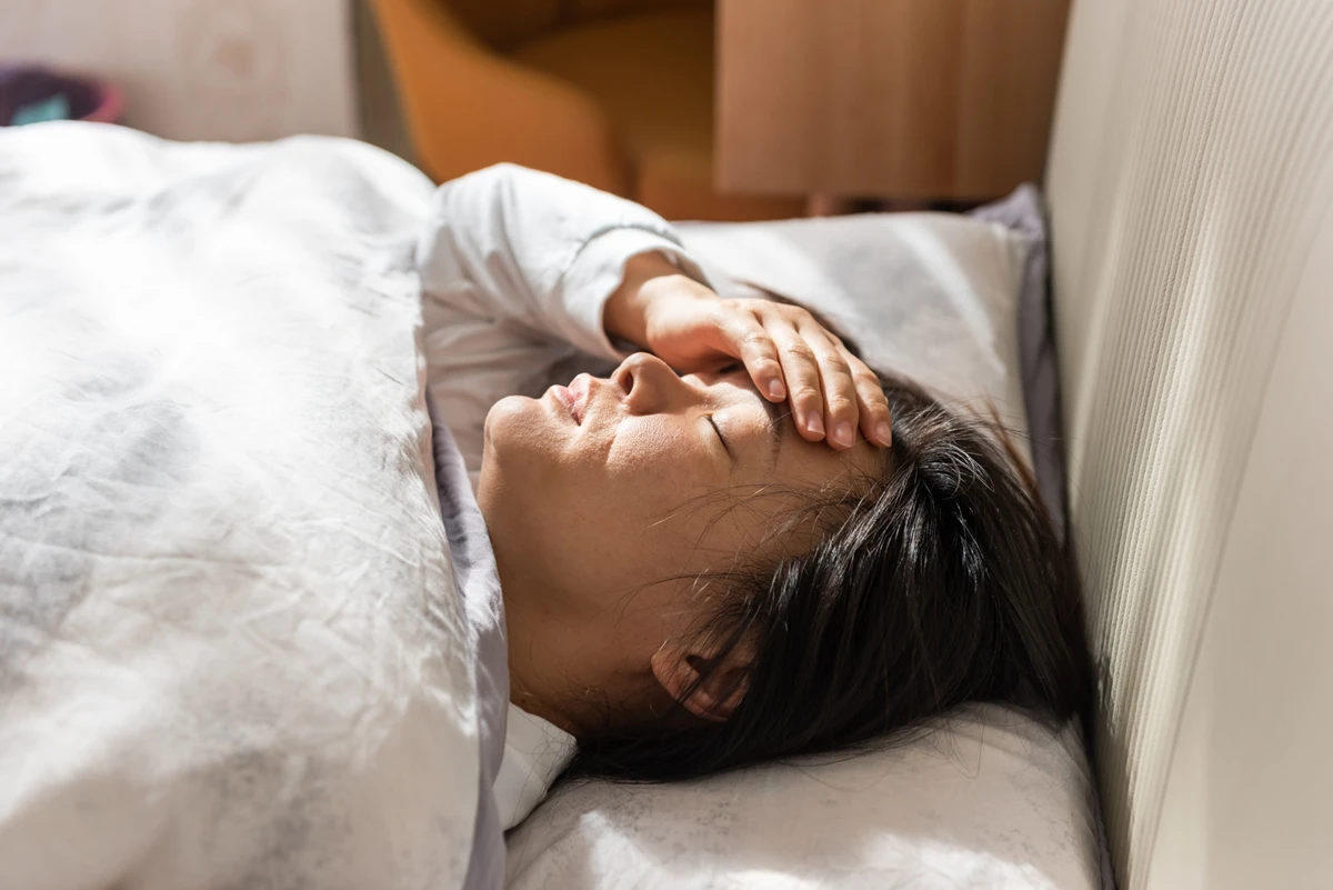 1 de 1 Jovem mulher asiática com a mão no rosto deitada em cama - Metrópoles - Foto: Getty Images