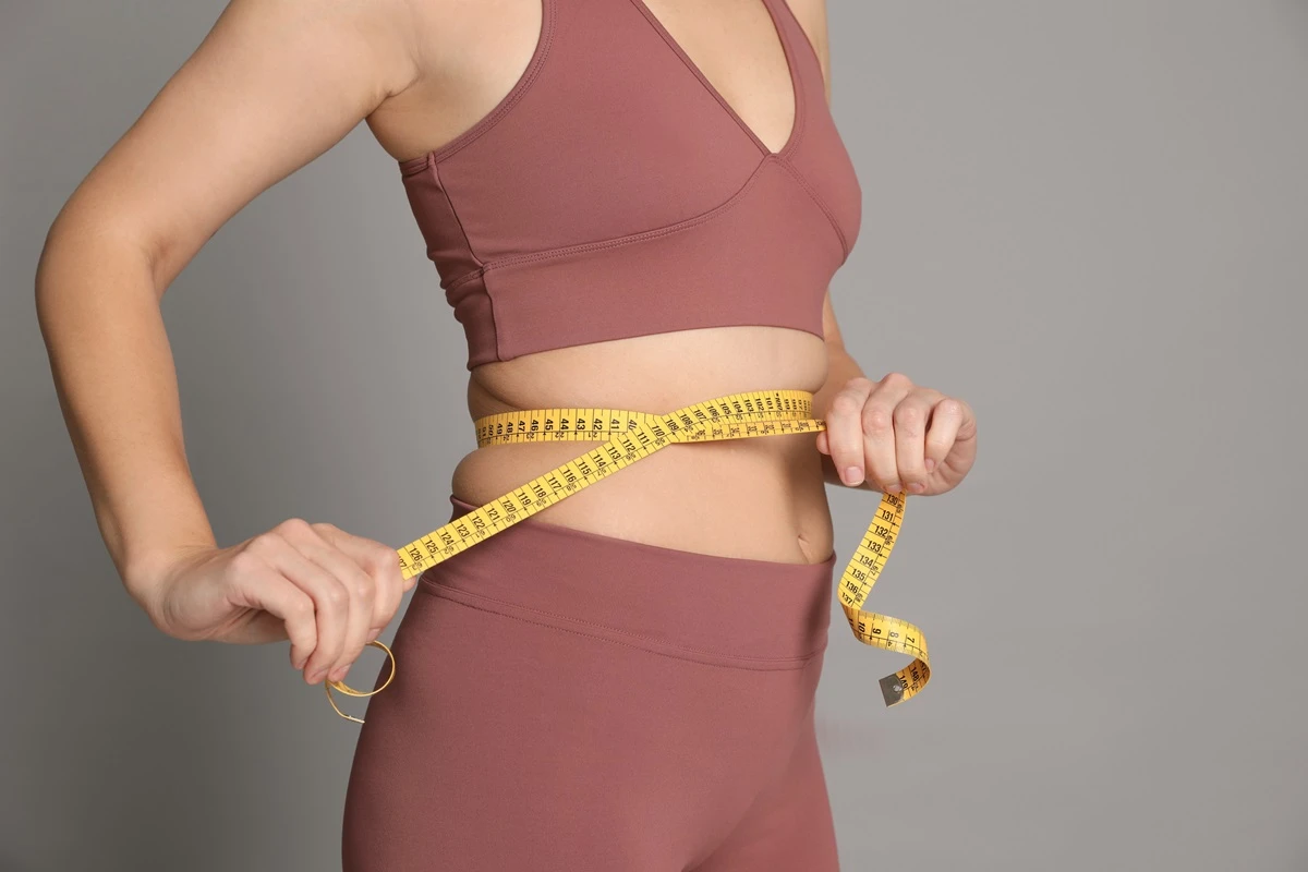 1 de 1 Foto colorida de mulher com fita métrica na barriga. Ela usa um cropped e uma legging - M...
