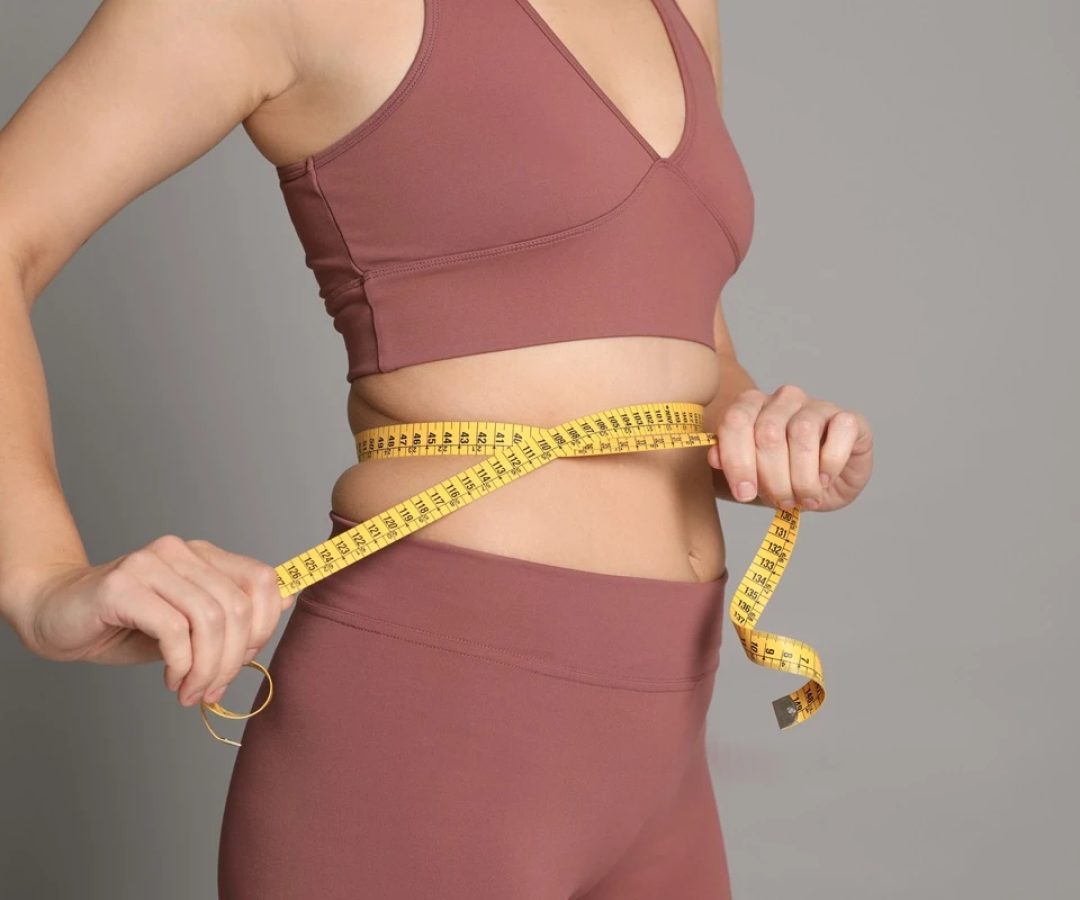 1 de 1 Foto colorida de mulher com fita métrica na barriga. Ela usa um cropped e uma legging - M...