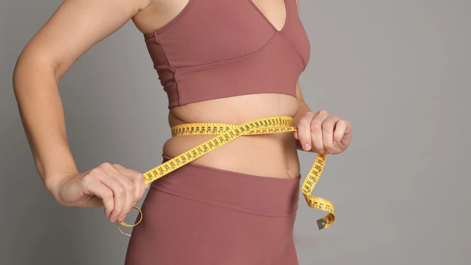 1 de 1 Foto colorida de mulher com fita métrica na barriga. Ela usa um cropped e uma legging - M...