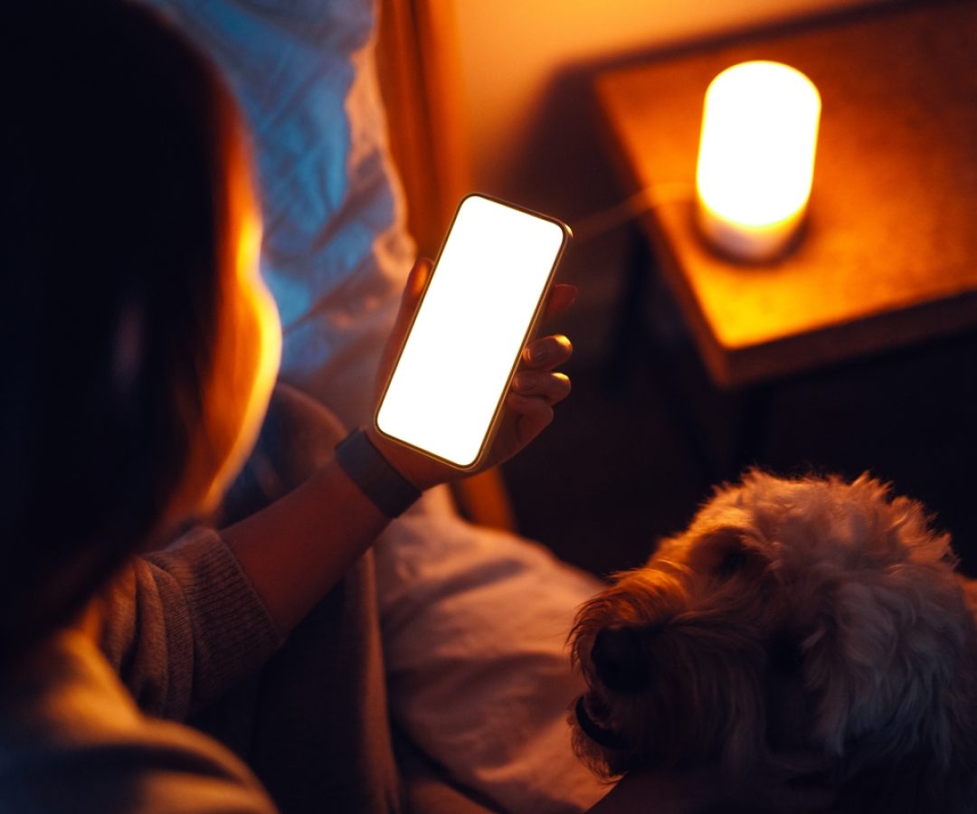 1 de 1 mulher mexendo no celular ao lado de cachorro - Foto: Oscar Wong/Getty Images