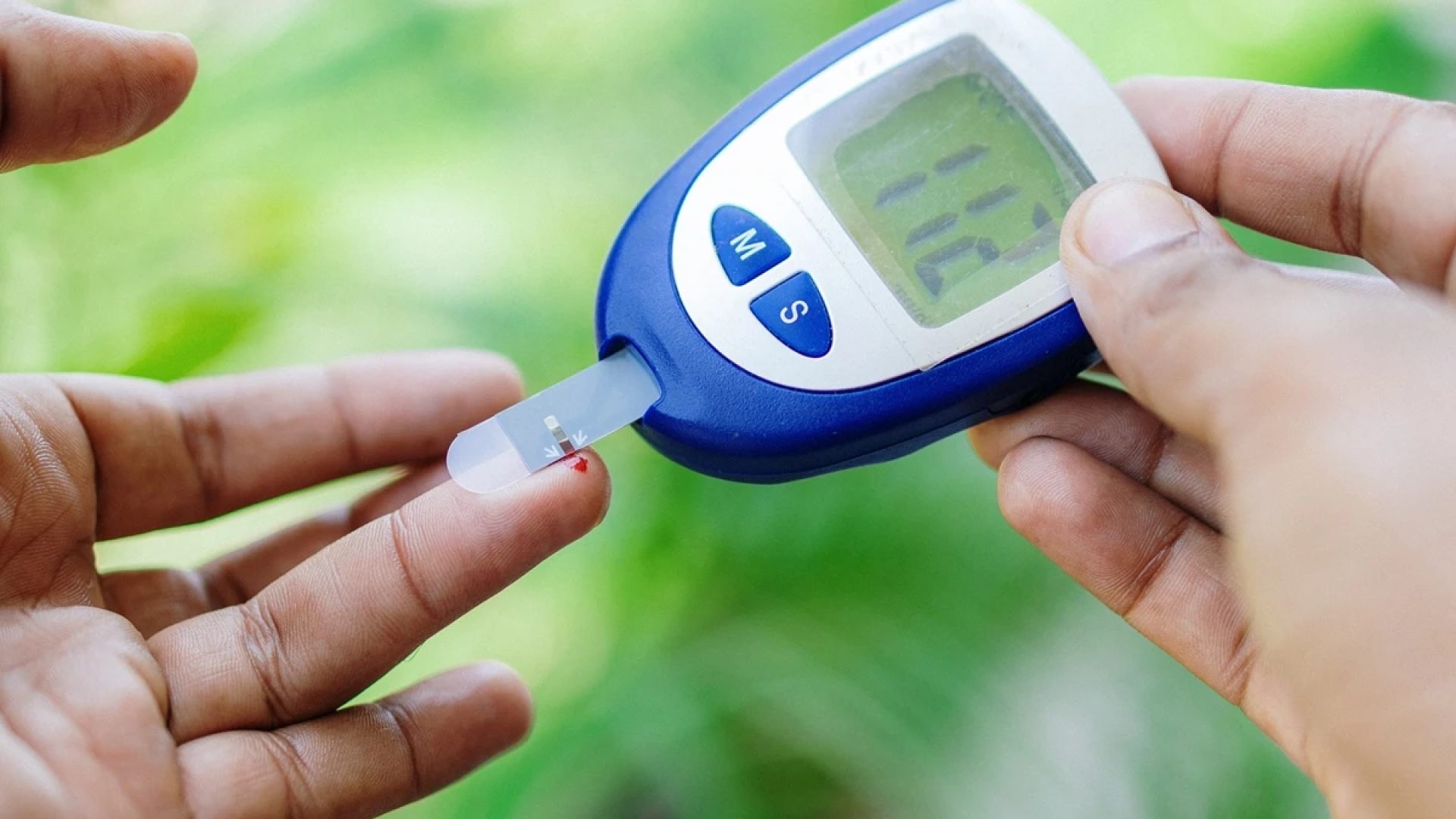 Imagem em close-up de mãos medindo a glicemia com um glicosímetro - Diabetes cresce 135% no Bra...