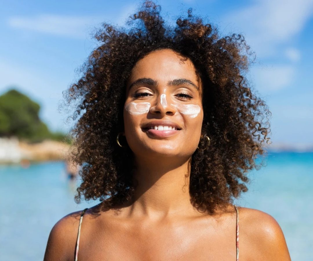 1 de 1 Foto colorida de mulher em praia e com protetor solar no rosto - Metrópoles - Foto: RgStu...