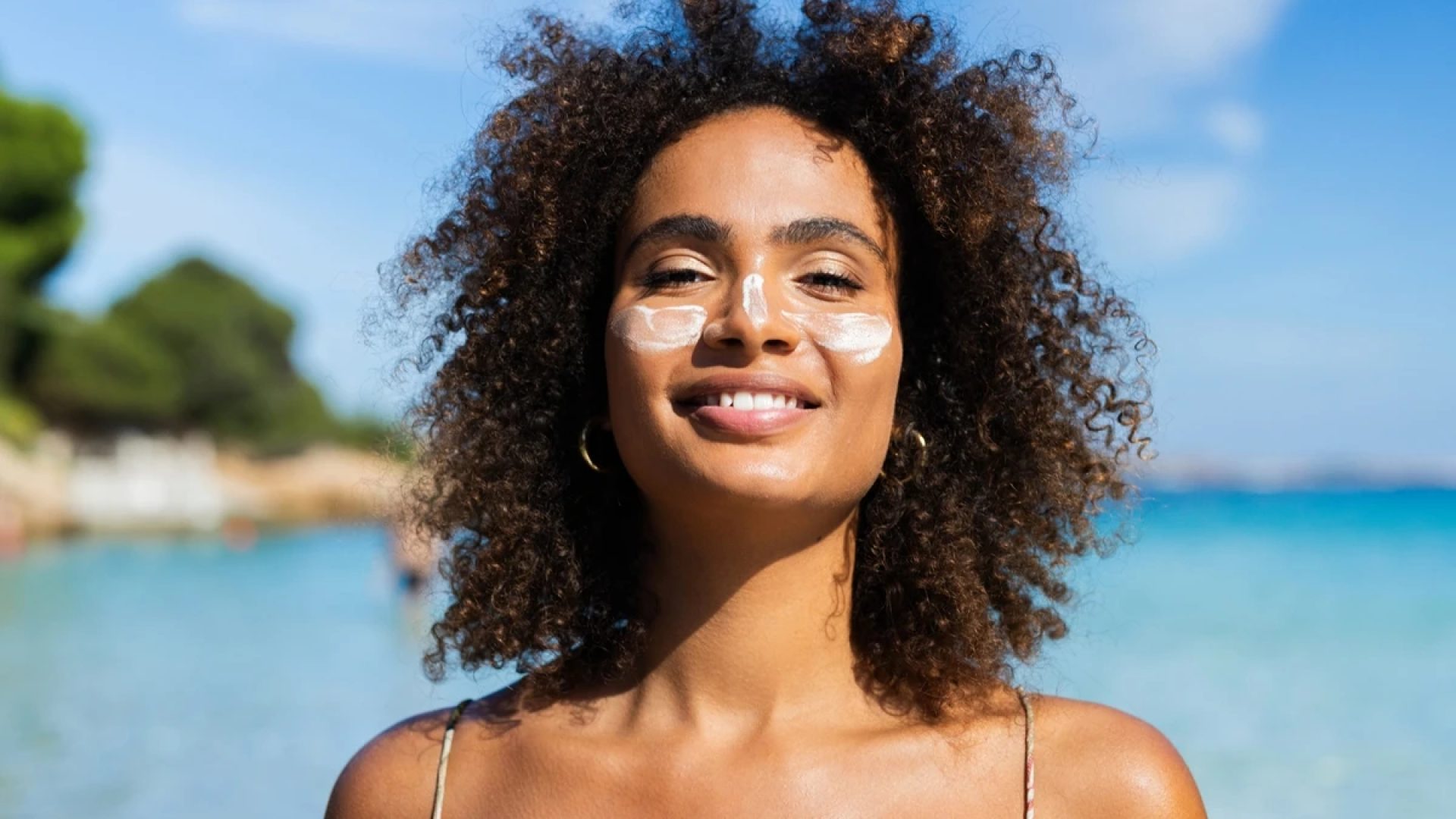 1 de 1 Foto colorida de mulher em praia e com protetor solar no rosto - Metrópoles - Foto: RgStu...